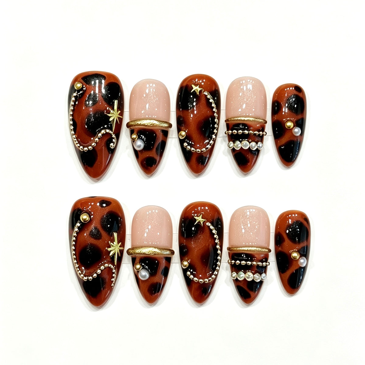 Amber tortoiseshell press-on nails with gold stars, pearl chains and black accents